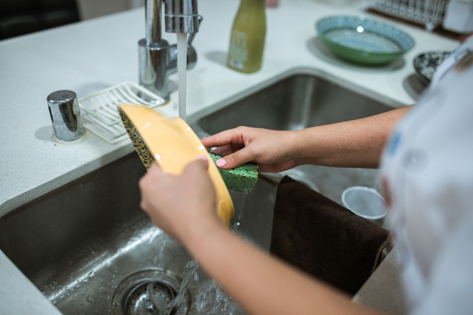 A young person washing up at the kitchen sink