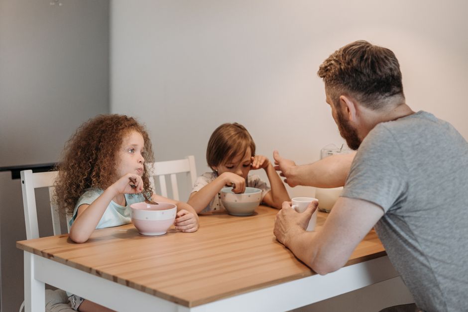 A parent sitting at a table talking with two children