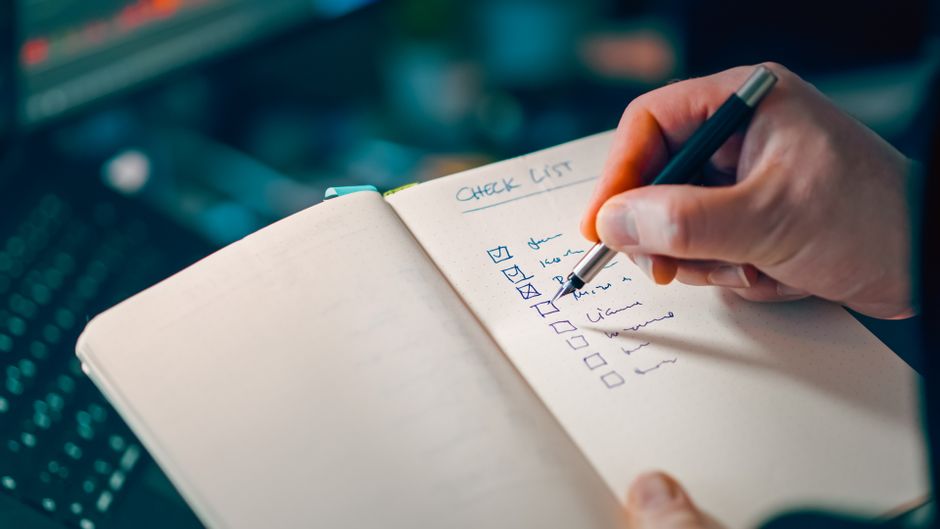 A hand ticking items off a checklist in a notebook