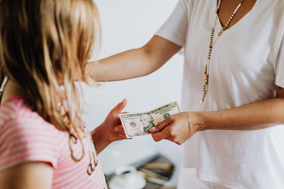 A parent handing a banknote to a child