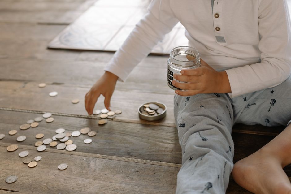 A child dropping coins into a glass jar