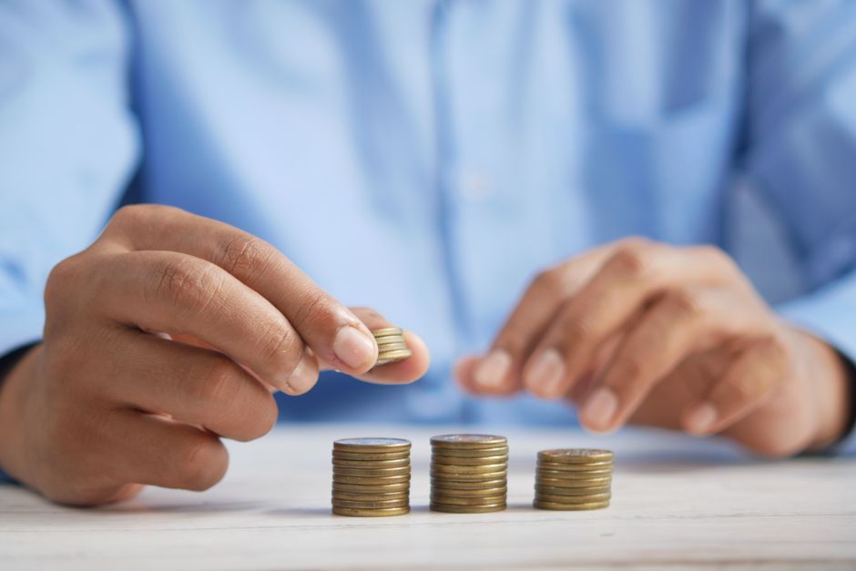 A person stacking coins into growing columns